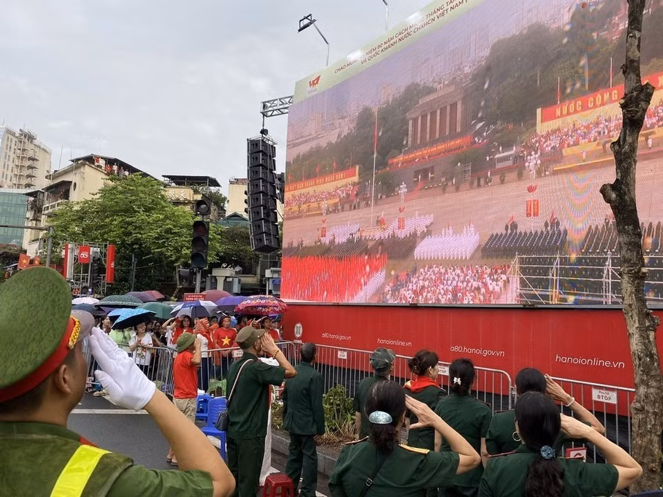 La gente en el área de Cua Nam realiza la ceremonia de izado de la bandera a través de una transmisión en vivo. (Foto: Vu Sinh - VNA)