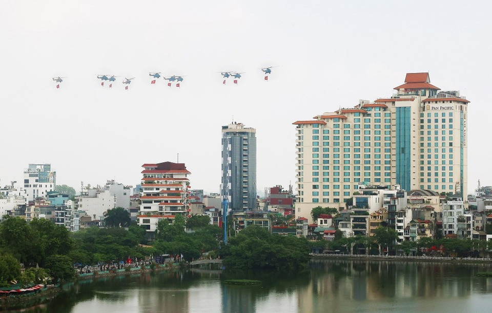 Una formación de 10 helicópteros de la Fuerza Aérea lleva la bandera del Partido y la bandera nacional. (Foto: Pham Kien - VNA)