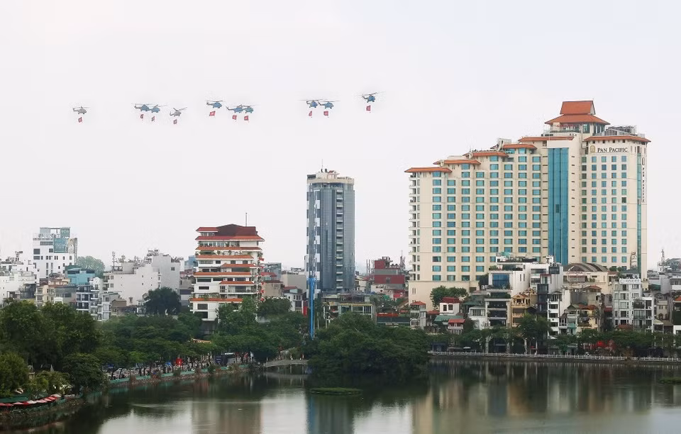 Una formación de 10 helicópteros de la Fuerza Aérea lleva la bandera del Partido y la bandera nacional. (Foto: Pham Kien - VNA)