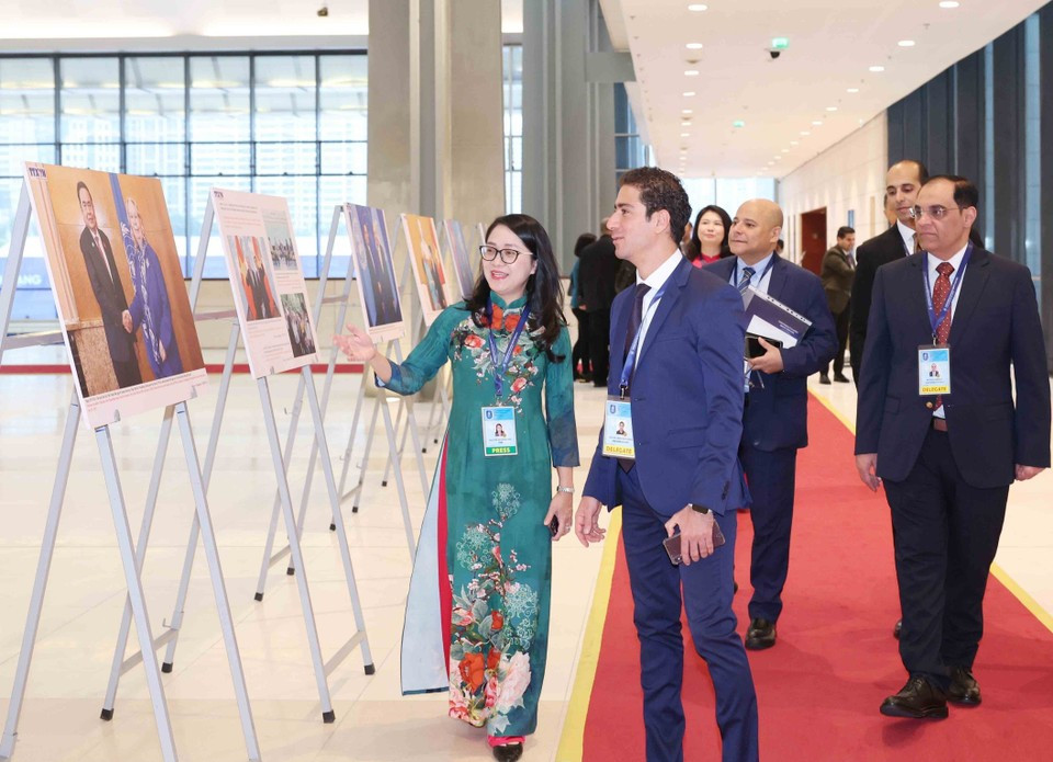 Delegados internacionales recorren la exposición fotográfica de la VNA durante la ceremonia de firma de la Convención de Hanoi, en la mañana del 25 de octubre. (Foto: VNA)