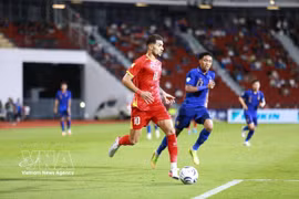 Hoang Hen de Vietnam (n.º 10) intenta avanzar con el balón ante un jugador tailandés.