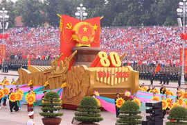 Un vehículo en miniatura con el emblema nacional de la República Socialista de Vietnam encabeza el desfile militar y la procesión multitudinaria. (Foto: VNA)