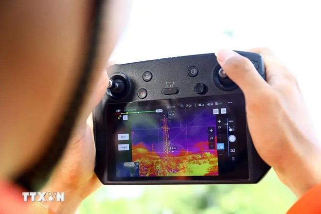 Un trabajador de transmisión eléctrica Binh Dinh utiliza un vehículo aéreo no tripulado (UAV) con una cámara termográfica para verificar la emisión de calor de los equipos en la línea eléctrica. (Foto: VNA) 1.webp