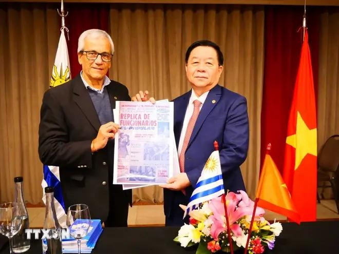 El secretario general del Partido Comunista de Uruguay, Juan Castillo, entrega al jefe de la Comisión de Propaganda y Educación del Comité Central del Partido Comunista de Vietnam, Nguyen Trong Nghia, un artículo sobre la visita del Presidente Ho Chi Minh a Montevideo en 1920, publicado en El Polular, portavoz del Partido Comunista de Uruguay. (Fuente: VNA) 1.webp