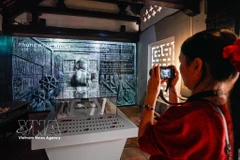 Los visitantes disfrutan de la exposición "La historia de la piedra preserva la memoria", que presenta un formato tradicional combinado con soluciones de tecnología digital (Foto: VNA)