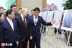 El primer ministro de Vietnam, Pham Minh Chinh (izquierda), y el presidente ruso, Vladimir Putin (centro), visitan una exposición fotográfica sobre la cooperación entre los dos países. (Foto: VNA)