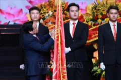 El primer ministro Pham Minh Chinh coloca la Orden Ho Chi Minh en la bandera tradicional de la VOV (Foto: VNA)