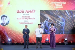 La directora general de la VNA, Vu Viet Trang (derecha), y el vicepresidente permanente de la Asociación de Periodistas de Vietnam, Nguyen Duc Loi (izquierda), entregan el primer premio a Pham Tuan Anh en el evento. (Foto: VNA)