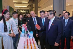 El primer ministro de Vietnam, Pham Minh Chinh, visita el stand del grupo TH al margen de la ceremonia de anuncio de productos que reciben reconocimiento de Marca Nacional. (Foto: Vietnam+)