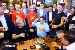 El primer ministro de Vietnam, Pham Minh Chinh, y el director ejecutivo de NVIDIA, Jensen Huang, disfrutan de la comida callejera de Hanoi el 5 de diciembre de 2024. (Foto: VNA)