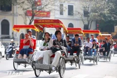 Turistas extranjeros experimentan un recorrido en triciclo alrededor del lago Hoan Kiem en Hanoi (Foto: VMA)