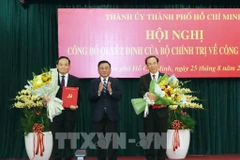 El miembro del Buró Político y permanente del Secretariado del Comité Central del PCV, Tran Cam Tu, entrega las decisiones del Buró Político a Tran Luu Quang y Nguyen Van Nen (Foto: VNA)
