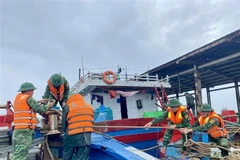 Las autoridades ayudan a los pescadores a amarrar los barcos (Foto: VNA)