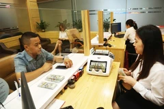 Clientes realizan transacciones en el banco Agribank (Foto: https://hanoimoi.vn/)