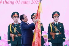 El primer ministro de Vietnam, Pham Minh Chinh, coloca la insignia “Héroe de las Fuerzas Armadas Populares” en la bandera tradicional de las fuerzas armadas de Ciudad Ho Chi Minh. (Foto: VNA)