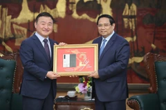 El primer ministro Pham Minh Chinh (derecha) entrega una placa conmemorativa de la producción del teléfono móvil número dos mil millones de Samsung en Vietnam a Roh Tae Moon (Foto: baochinhphu.vn)