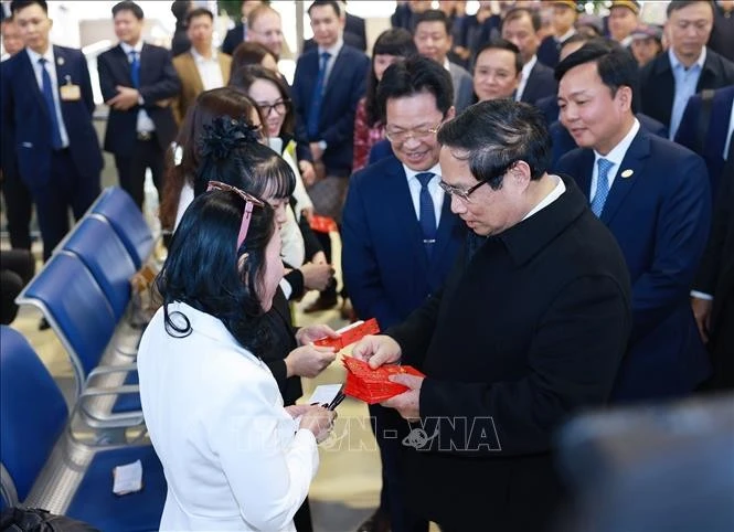 El primer ministro vietnamita, Pham Minh Chinh, entrega dinero de la suerte a los pasajeros en la estación de tren de Hanoi. (Fuente: VNA)