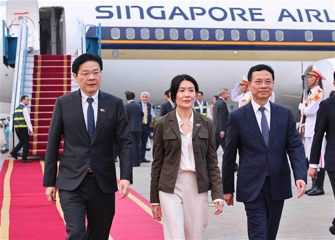 El ministro vietnamita de Ciencia y Tecnología, Nguyen Manh Hung, recibe al primer ministro de Singapur, Lawrence Wong, y su esposa en el aeropuerto de Noi Bai. (Fuente: VNA)