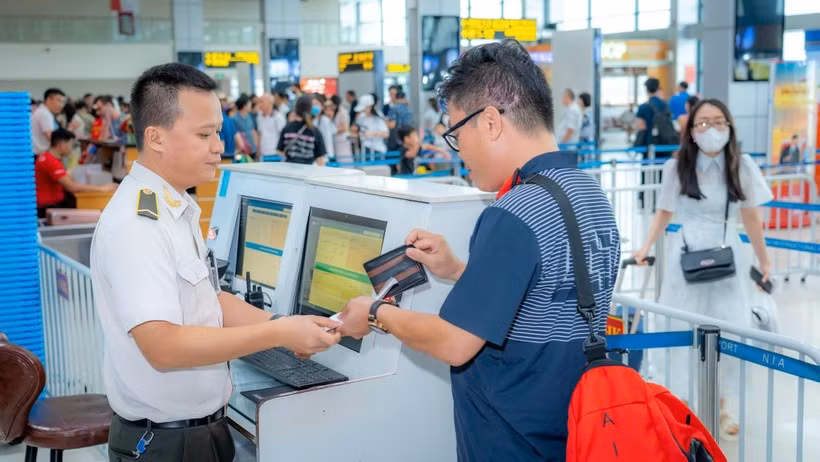 Personal de seguridad aérea verifica los documentos del pasajero antes de abordar el avión. (Fuente: VietnamPlus) 