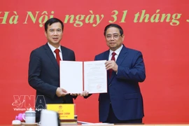 El primer ministro Pham Minh Chinh (derecha) entrega la decisión de nombramiento de Bui The Duy como director de la Universidad Nacional de Hanoi. (Foto: VNA)