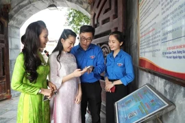 Jóvenes guían a los turistas para que escaneen códigos QR y aprendan sobre el sitio histórico de la Victoria de Xuong Giang. (Foto: VNA)