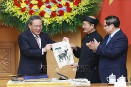 El primer ministro vietnamita, Pham Minh Chinh (derecha), y su par chino, Li Qiang, experimentaron de primera mano la creación de una pintura popular de la etnia Dong Ho. (Foto: VNA)