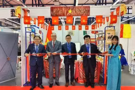 El embajador Tran Quoc Khanh (centro) y el consejero comercial Hoang Duc Nhuan (izquierda) cortaron la cinta para inaugurar el pabellón de Vietnam en la feria. (Foto: VNA)