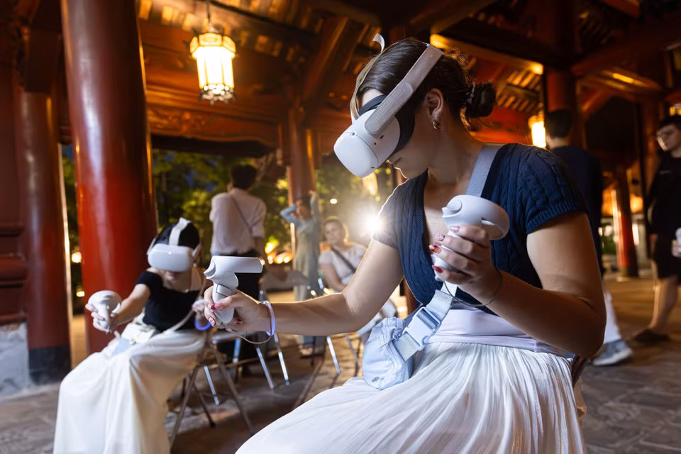 Turistas extranjeros utilizan dispositivos de realidad virtual para explorar espacios culturales del patrimonio en el tour nocturno. Foto: VNA