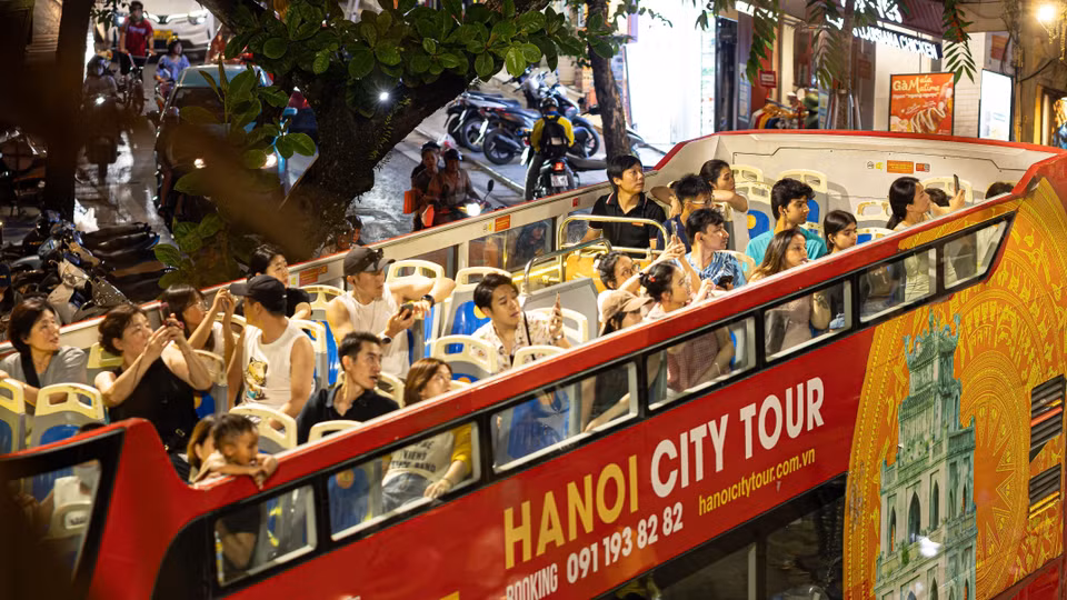 Numerosos turistas nacionales y extranjeros disfrutan contemplando la panorámica de Hanoi de noche desde el espacio abierto del segundo piso de los autobuses turísticos. Foto: VNA