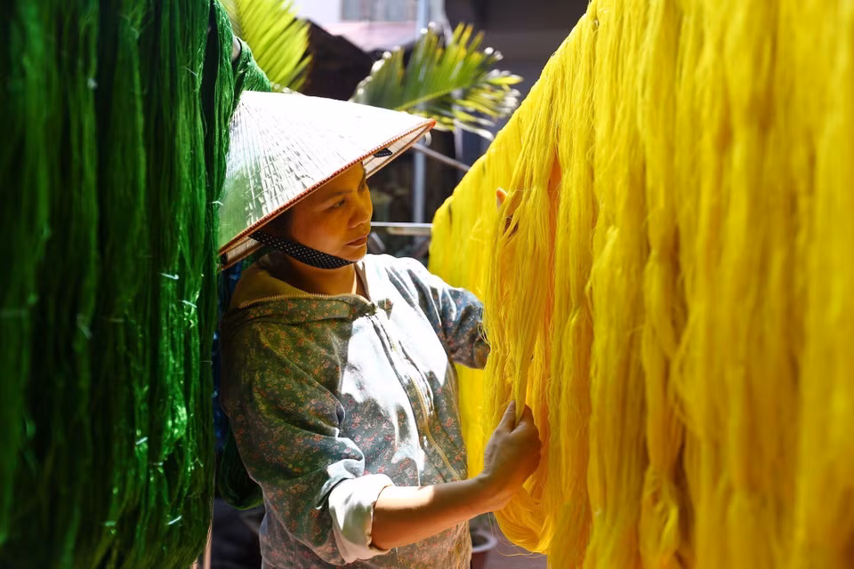 Secando el hilo de seda después de ser teñido en el taller del artesano Nguyen Anh Son en el pueblo de seda Vạn Phuc. Foto: VNA