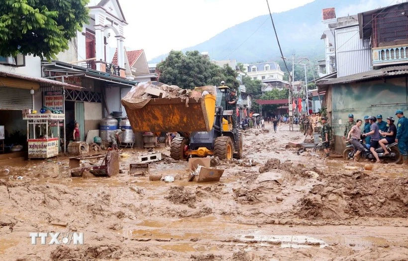 Se movilizaron excavadoras para nivelar y recoger el lodo, las ramas de árboles y la basura arrastrada por la reciente inundación en la comuna de Song Ma, provincia de Son La. (Foto: VNA) 