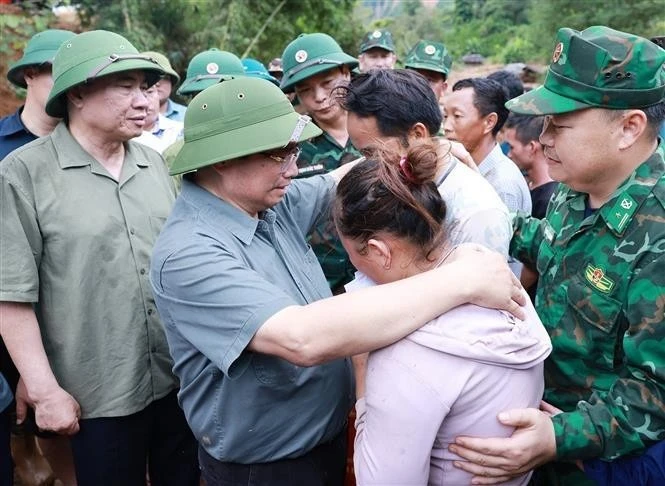 El primer ministro Pham Minh Chinh consuela a una familia cuyo miembro falleció en las recientes inundaciones en la comuna de Xa Dung. (Foto: VNA) 