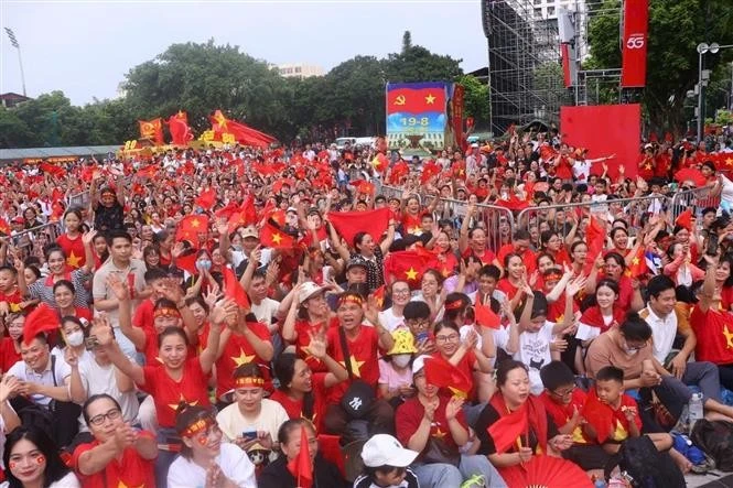Numerosas personas con banderas rojas y estrellas amarillas en la intersección de Hung Vuong y Tran Phu esperan para presenciar el ensayo. (Foto: VNA) 