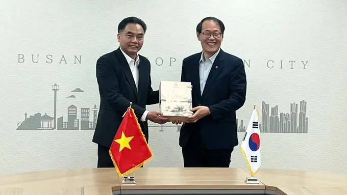 Nguyen Loc Ha, vicepresidente del Comité Popular de Ciudad Ho Chi Minh, entrega un regalo al vicealcalde de la urbe surcoreana de Busán, Lee Jun Seung. (Foto: sggp.org.vn)