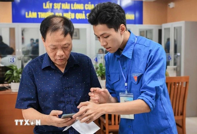 Miembros de la Unión de Jóvenes Comunistas Ho Chi Minh orientan a las personas sobre cómo utilizar y declarar servicios públicos en línea en teléfonos inteligentes. (Foto: VNA)