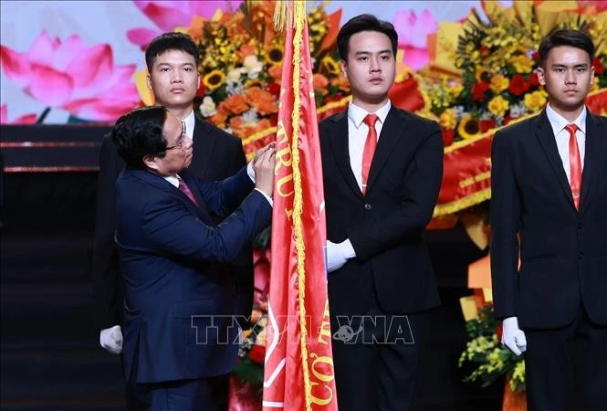 El primer ministro Pham Minh Chinh coloca la Orden Ho Chi Minh en la bandera tradicional de la VOV (Foto: VNA) 