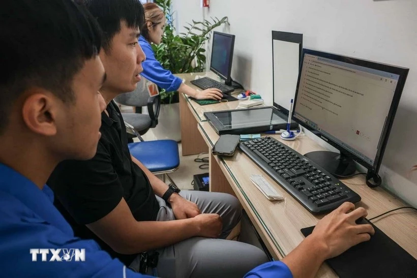 Los voluntarios jóvenes guían a las personas para declarar en línea y hacer certificados de nacimiento para sus hijos en el punto de servicio administrativo público del barrio de Cua Nam. (Foto: VNA)