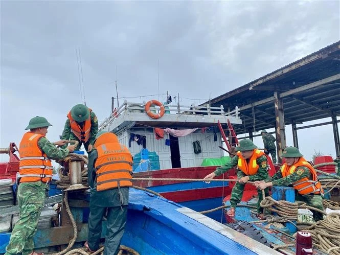 Las autoridades ayudan a los pescadores a amarrar los barcos (Foto: VNA)
