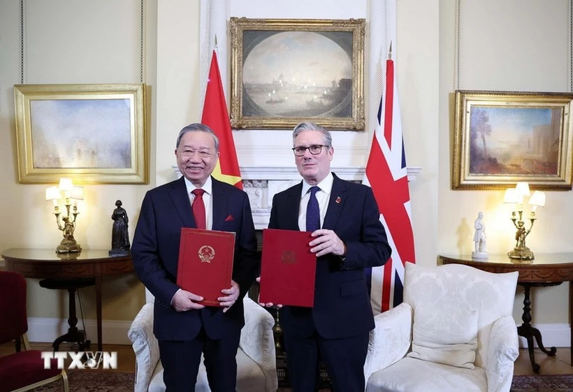 El secretario general del Partido Comunista de Vietnam, To Lam, y el primer ministro de Reino Unido, Keir Starmer, entregan la Declaración conjunta sobre la elevación de los nexos bilaterales a una asociación estratégica integral. (Foto: VNA)