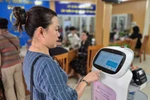 Ciudadana interactúa con un robot de IA que aplica tecnología de inteligencia artificial para ayudar en la realización de trámites administrativos en Hanoi. Foto: VNA