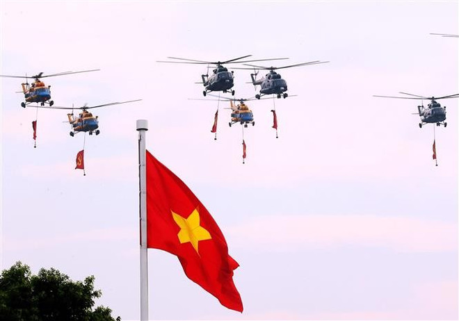 Al inaugurar el desfile, el escuadrón de helicópteros de la Fuerza Aérea Popular, con la bandera del Partido y la bandera nacional, ondeó sobre la plaza Ba Dinh. (Foto: Van Diep - VNA) vna-potal-man-trinh-dien-cua-cac-bien-doi-may-bay-mo-dau-chuong-trinh-dieu-binh-a80-8250187.jpg