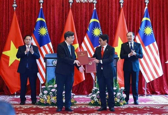 El primer ministro vietnamita, Pham Minh Chinh (izq.), y su homólogo malasio, Anwar Ibrahim, presencian el intercambio de una carta de intención de cooperación entre la Universidad Nacional de Vietnam, Ciudad Ho Chi Minh, y la Universidad Nacional de Malasia. (Foto: VNA) vna-potal-thu-tuong-pham-minh-chinh-hoi-dam-voi-thu-tuong-malaysia-anwar-ibrahim-8053378.jpg