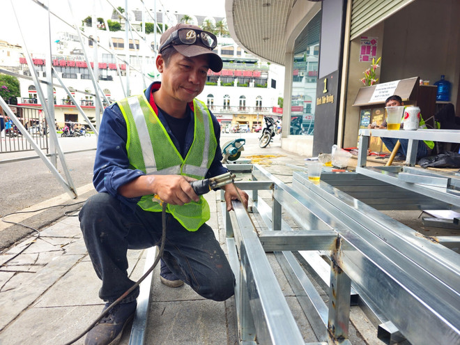 Los trabajadores instalan barreras. (Foto: VNA) vna-potal-ha-noi-bat-dau-thao-do-di-chuyen-cac-trang-thiet-bi-va-ha-giai-cong-trinh-toa-nha-ham-ca-map-8053546.jpg