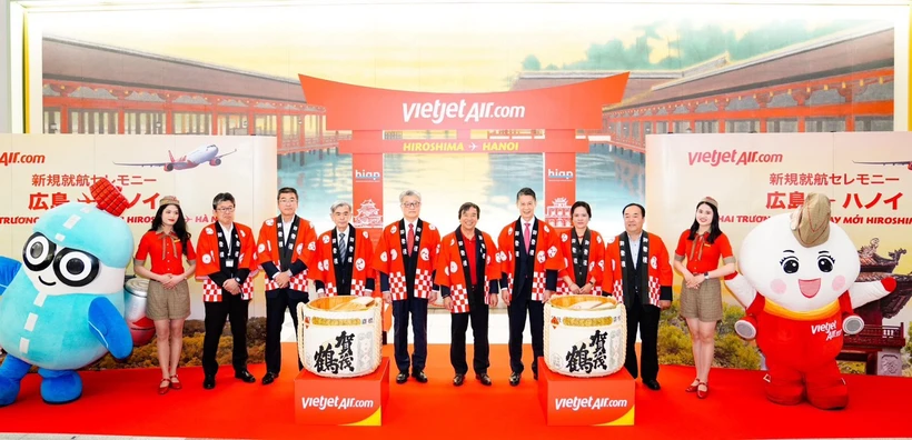 La cónsul general de Vietnam en Fukuoka Vu Chi Mai (tercera de la derecha), el gobernador de la prefectura de Hiroshima Yuzaki Hidehiko (cuarto de la derecha), el director general adjunto de Vietjet, Nguyen Duc Thinh (quinto de la derecha) y el presidente y director representante del Aeropuerto Internacional de Hiroshima, Yasuhiro Nakamura (quinto de la izquierda) junto con otros delegados en el escenario en la ceremonia para lanzar el primer vuelo que conecta Hiroshima y Hanoi. (Fuente: Vietjet)