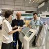 Las empresas muestran maquinaria moderna a los visitantes de la exposición. (Foto: VNA)