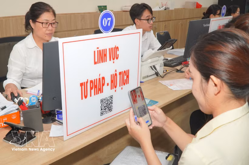 Ciudadanos escanean códigos QR para consultar trámites y procesos administrativos relacionados con los sectores de justicia y registro civil. (Foto: VNA)