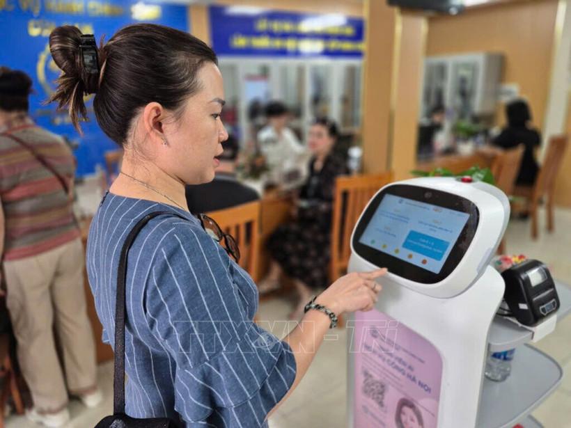 Ciudadana interactúa con un robot de IA que aplica tecnología de inteligencia artificial para ayudar en la realización de trámites administrativos en Hanoi. Foto: VNA