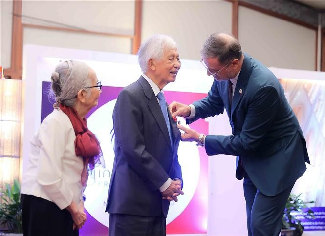 El embajador de Francia en Vietnam, Olivier Brochet, entrega la Orden Nacional de la Legión de Honor al profesor Jean Tran Thanh Van durante la ceremonia. (Foto: VNA)