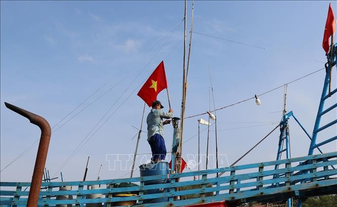 Pescadores izan la bandera de la Patria antes de zarpar para reafirmar la soberanía sobre las islas y mares de la Patria. (Foto: VNA)
