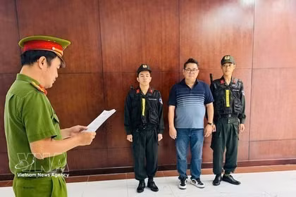El sospechoso, Nguyen Thanh Hiep, escucha mientras la agencia de investigación le entrega las decisiones procesales. (Foto: VNA)